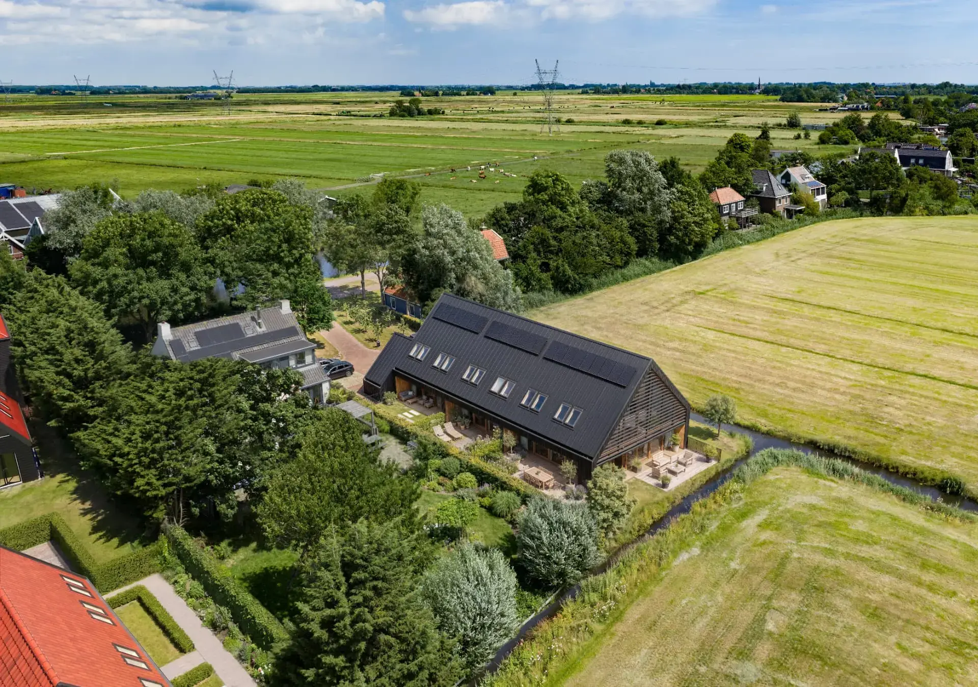 Luchtfoto van de drie woningen aan de Broekermeerdijk, omgeven door groen en water